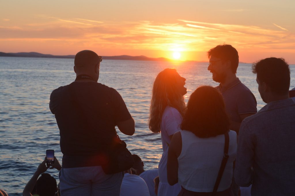Una pareja y otras personas disfrutan del sobrecogedor atardecer en Zadar, en el Órgano de Mar