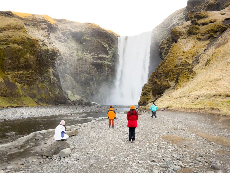 Cuatro personas en la cascada Skogafoss en Islandia
