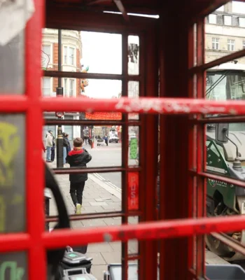 Un niño a través de una cabina de teléfono en el barrio de Chinatown, en Londres